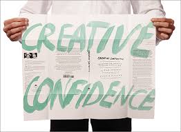 a man holding up a paper, and written on in in green, are the words creative confidence 