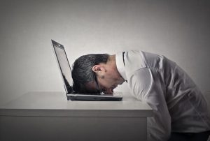 a man who is burnt out from sales has passed out with his head on his computer