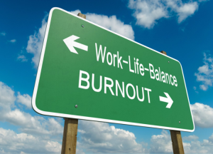 A hi way sign which is green and has the caption that says Work-life-balance with an arrow pointing one way, and another caption that says burnout with an arrow pointing the other way.